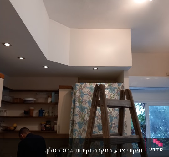 A kitchen under renovation with a wooden ladder and covered cabinets.